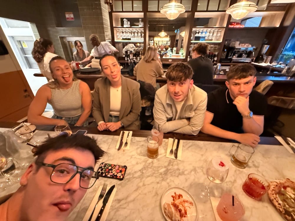 A group of staff sat around a dinner table at night looking happy.