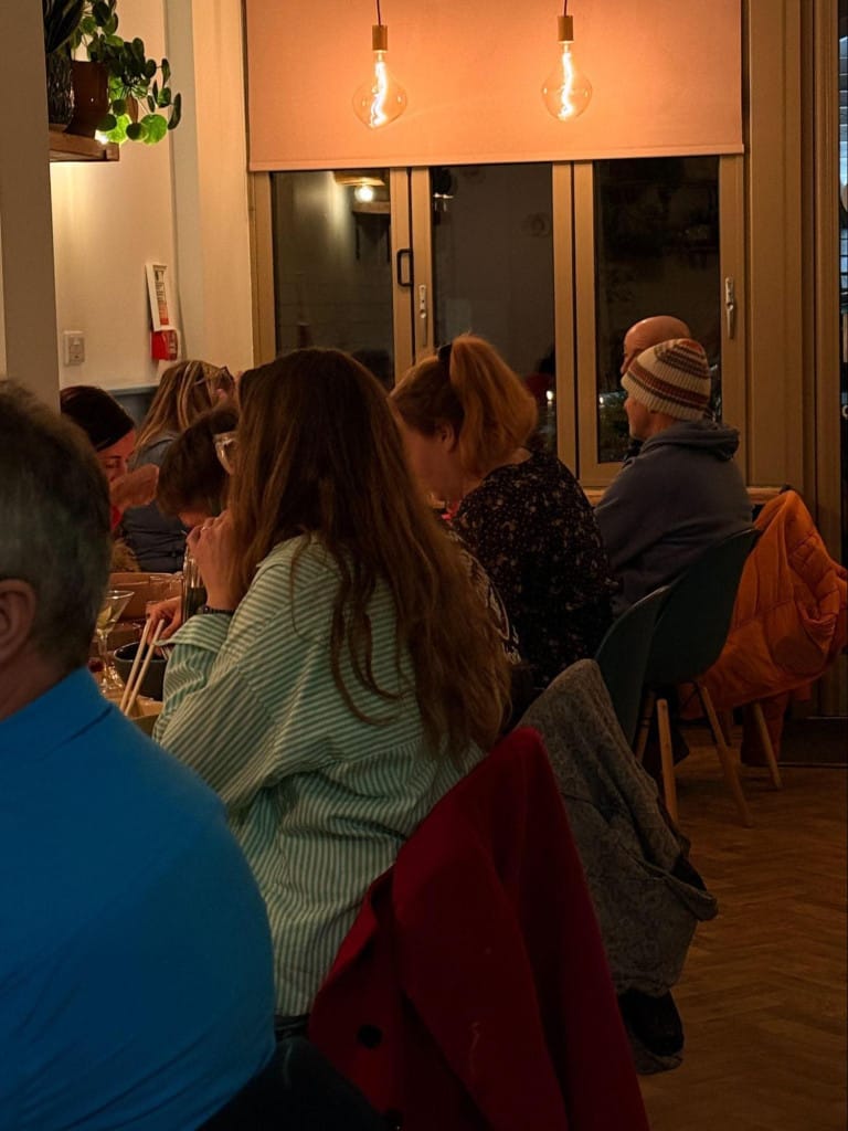People sat in a cosy cafe with warm lighting.