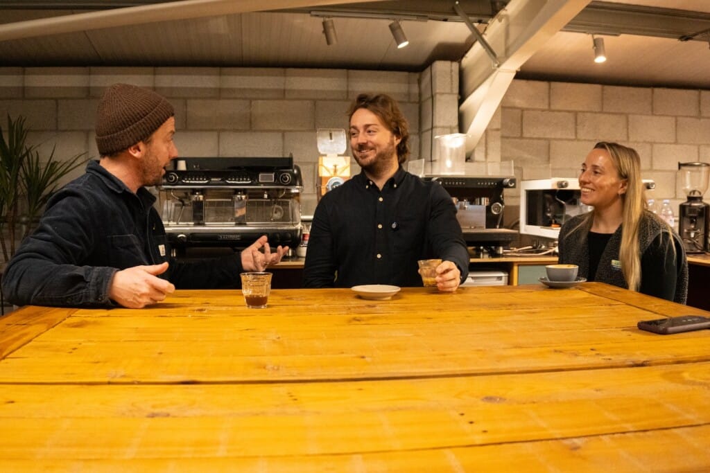 The Notos and Heartland team chatting and laughing around a table with coffee.