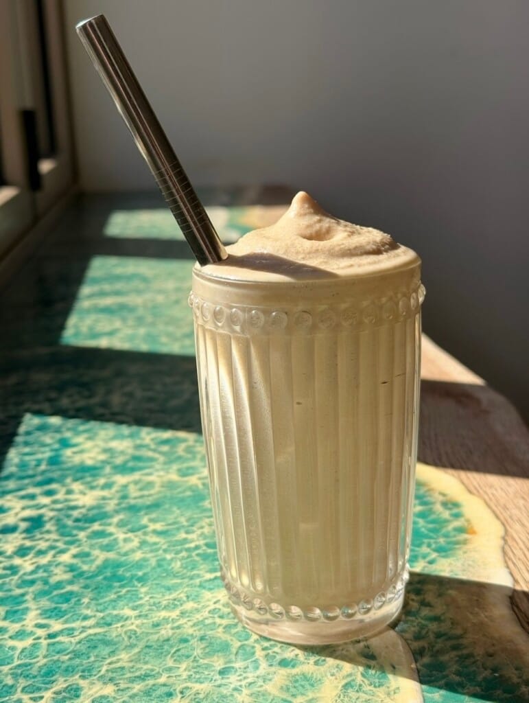 Photo of cold Spanish latte in a glass on a sunny table